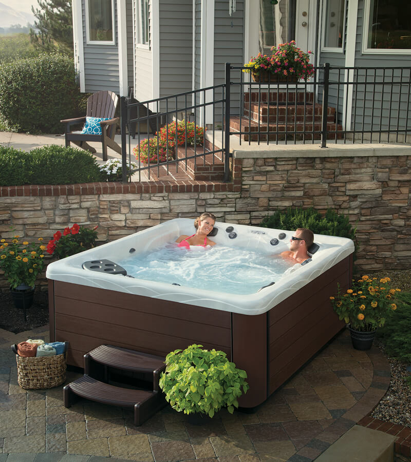 A couple relaxing in a Master Spas hot tub beside a home