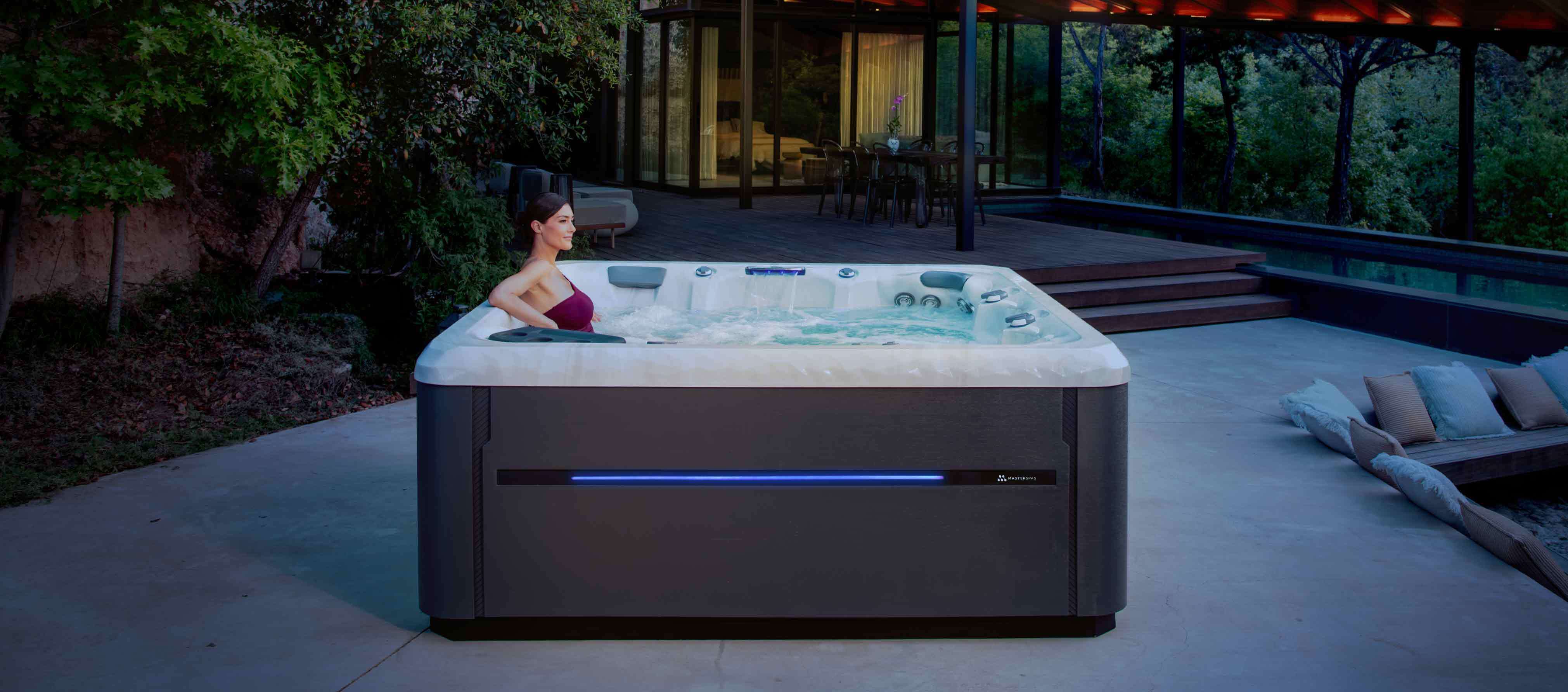 Master Spas hot tub on a patio beside a contemporary home at dusk